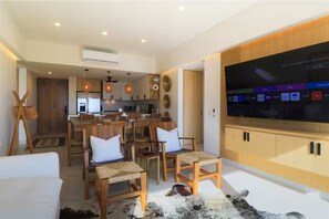 A modern living room with a flat-screen TV, wooden furniture, and a cowhide rug. - Luxury 2BR w/ Ocean Views • Gym • Jacuzzi • Infinity Pool • Walk Everywhere (Bucerías)