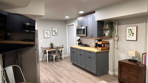 A modern kitchen with grey cabinets, a microwave, and a dining area with a table and chairs.