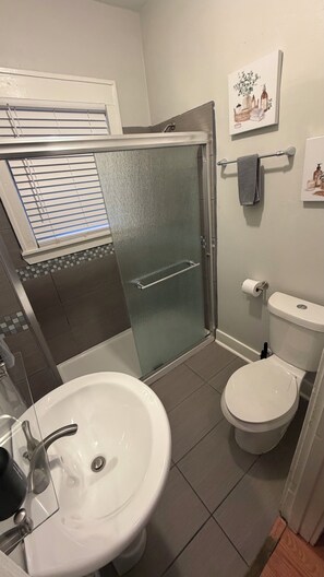 Een badkamer met douche, toilet en wastafel.