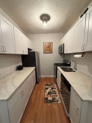 A kitchen with white cabinets, a black refrigerator, a stove, and a microwave.