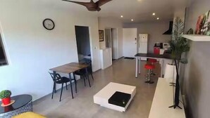 A modern living room with a dining area, a kitchen, and a ceiling fan. - Appartement Fun et Agréable (papeete)