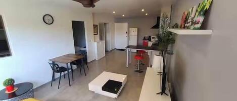 Een moderne woonkamer met een eetgedeelte, een keuken en een plafondventilator.