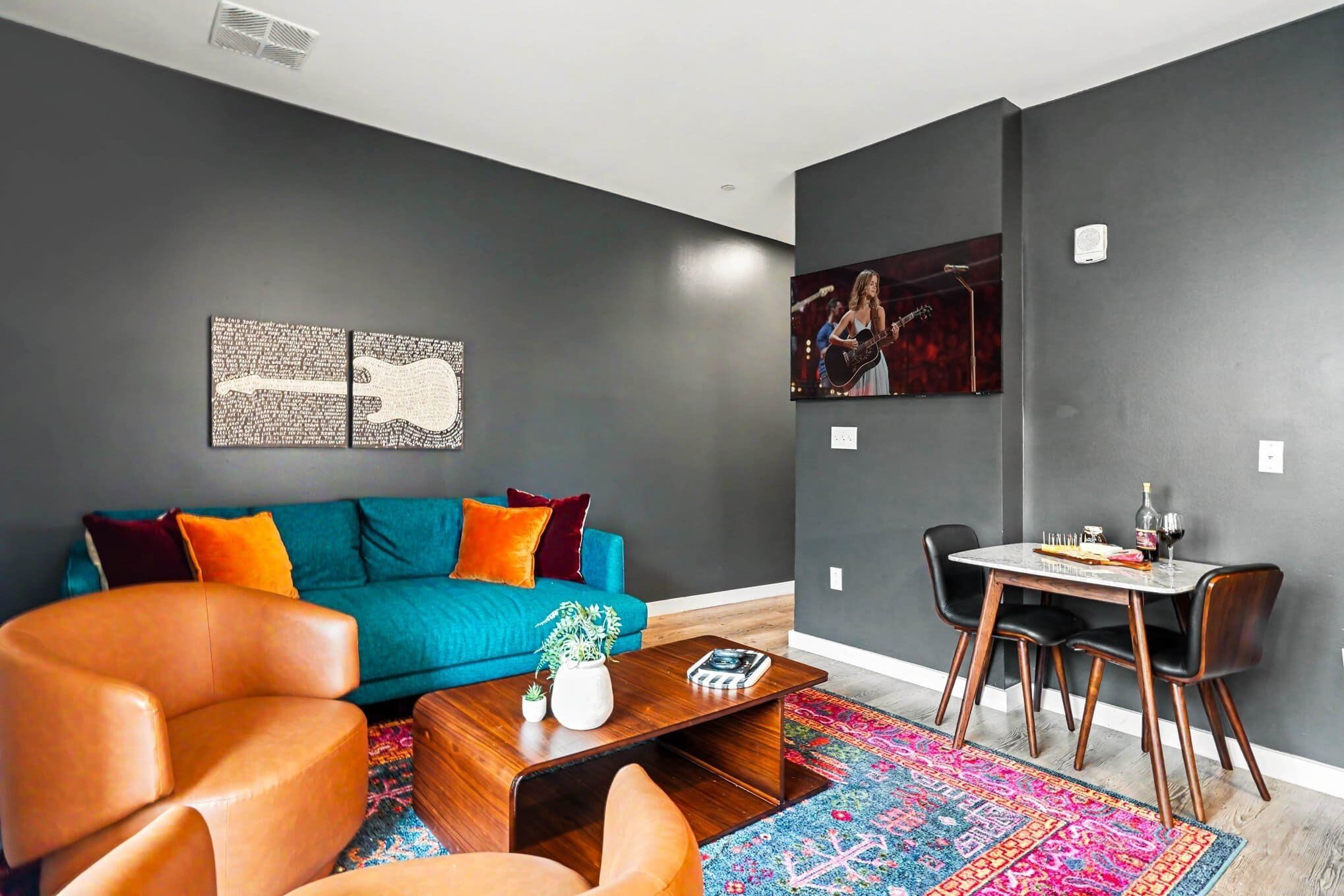 Una sala de estar moderna con un sofá color turquesa, un sillón naranja y una mesa de centro.