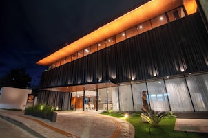 A modern building with a prominent overhang, large windows, and a well-lit entrance.