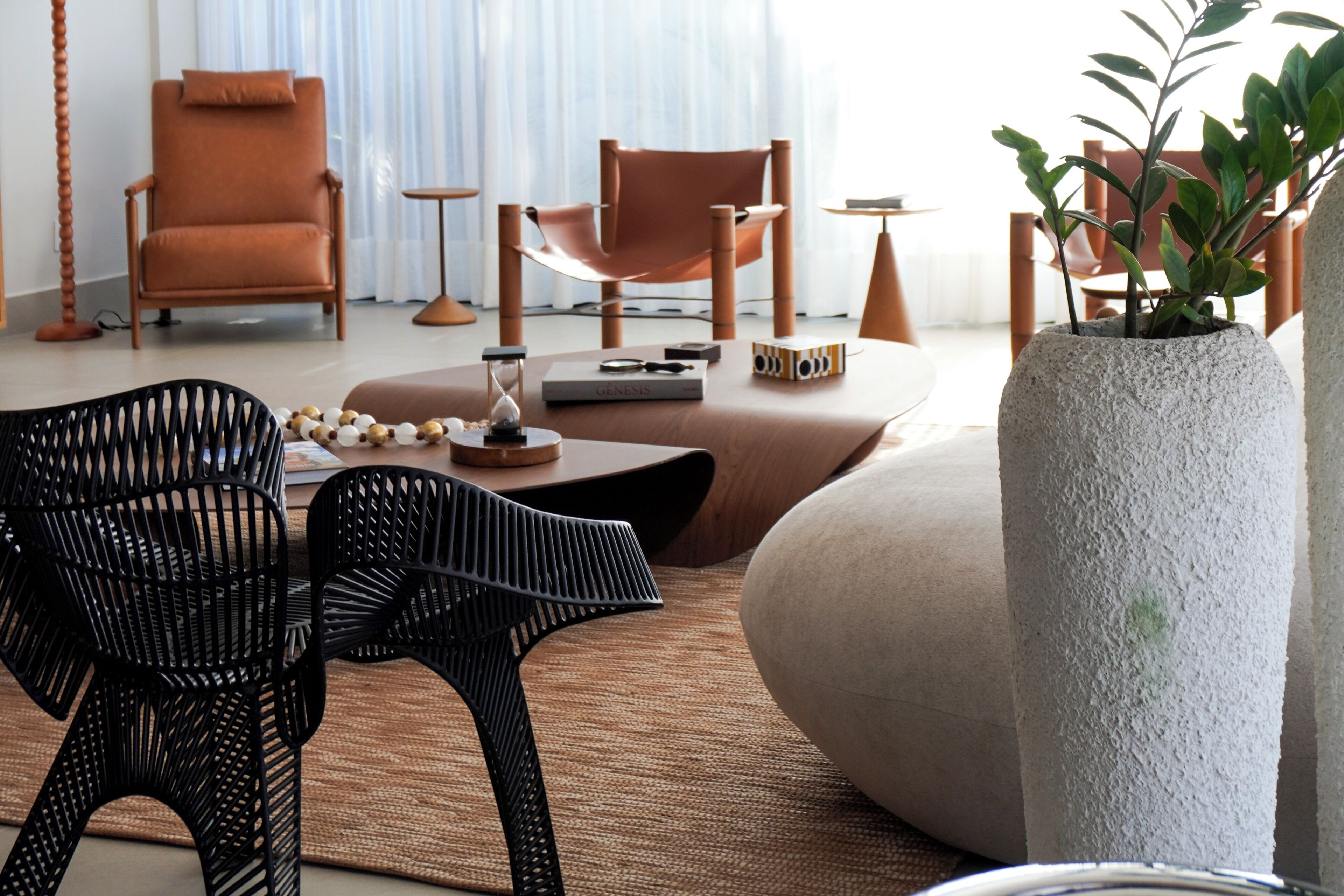 Uma sala de estar moderna com um sofá, duas poltronas, uma mesa de centro e um vaso de planta.
