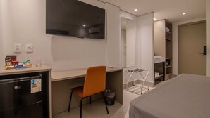 A hotel room with a bed, a desk, a chair, a TV, a mirror, and a wardrobe. - Hotel Mandu (Teresina)
