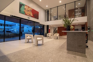 A lobby with a reception desk, seating area, and a large window overlooking a parking area.
