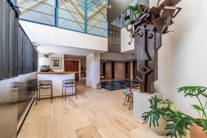 A spacious indoor area with a pool, seating, and a unique metal sculpture. - Suite Estudio de Lujo (Puerto Vallarta)