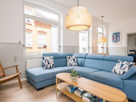 A modern living room with a sectional sofa, a wooden coffee table, and a hanging light fixture.