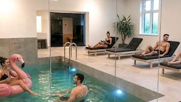 Piscina interna com espreguiçadeiras e um flutuador em forma de flamingo rosa.