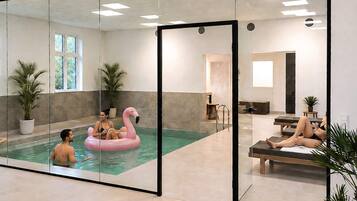 Piscina interior moderna com paredes de vidro, um boi de flamingo flutuante e área de lounge com assentos.