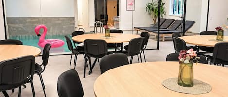 A modern conference room with round tables, black chairs, and a glass wall.
