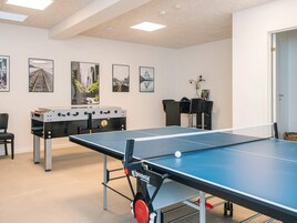 A room with a ping pong table, a foosball table, and four framed pictures on the wall.
