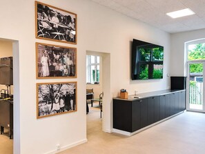 A modern kitchen with a black countertop and cabinets, a television mounted above the counter, and framed black-and-white photographs on the wall. - 4 Star Holiday Home in Aabenraa (Aabenraa)