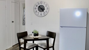 A kitchen with a white refrigerator, a wall clock, and a dining table with chairs. - Long term stay perfect for traveling professionals! Near downtown & hospitals! (Omaha)