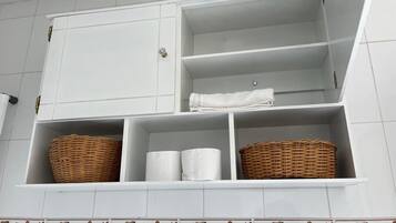 A bathroom with white cabinets, two wicker baskets, and two rolls of toilet paper.