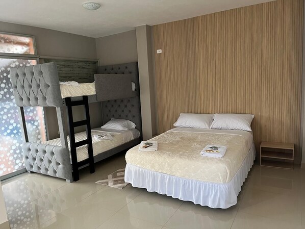 A bedroom with a bunk bed, a large bed, and a wooden panel wall.