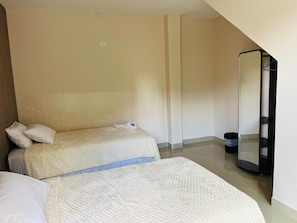 Una habitación de hotel con dos camas, un espejo grande y un bote de basura.