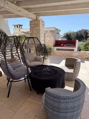 An outdoor seating area with wicker furniture, a stone pillar, and a television screen. - WHITE STONES HOUSE (Solo Locazione) Trulli e Lamie con piscina e mini spa. (Ostuni)