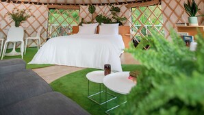 Interieur van een joert met een bed, zithoek en een centrale lamp.