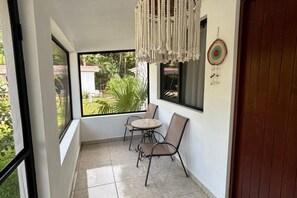 A balcony with a table and chairs, a macrame hanging, and a dreamcatcher on the wall.