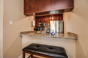A kitchen with wooden cabinets, stainless steel appliances, a granite countertop, and a black leather bench. - Walkable to Old Town, Hot Tub & Pool,  2 King Beds, Free Covered Parking (Scottsdale)
