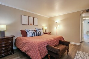 A bedroom with a large bed, two bedside tables, a nightstand, a chair, and a wall-mounted lamp. - Walkable to Old Town, Hot Tub & Pool,  2 King Beds, Free Covered Parking (Scottsdale)