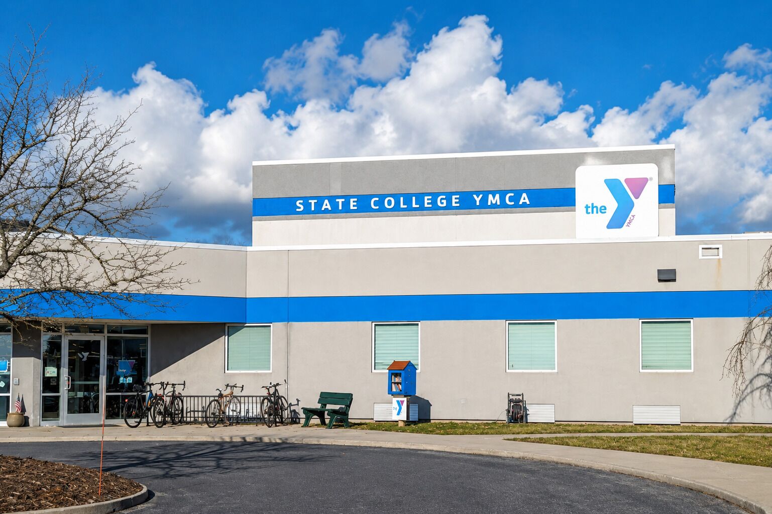 A building with 'STATE COLLEGE YMCA' signage, a blue awning, and a clear sky.