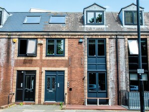 A row of terraced houses with a front door, windows, and a small bench outside. - 198 Portland Apartments by Rizalina (Newcastle upon Tyne)