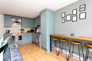 Una cocina moderna con armarios azul claro, encimera de madera, lavadora y una zona de bar con taburetes.