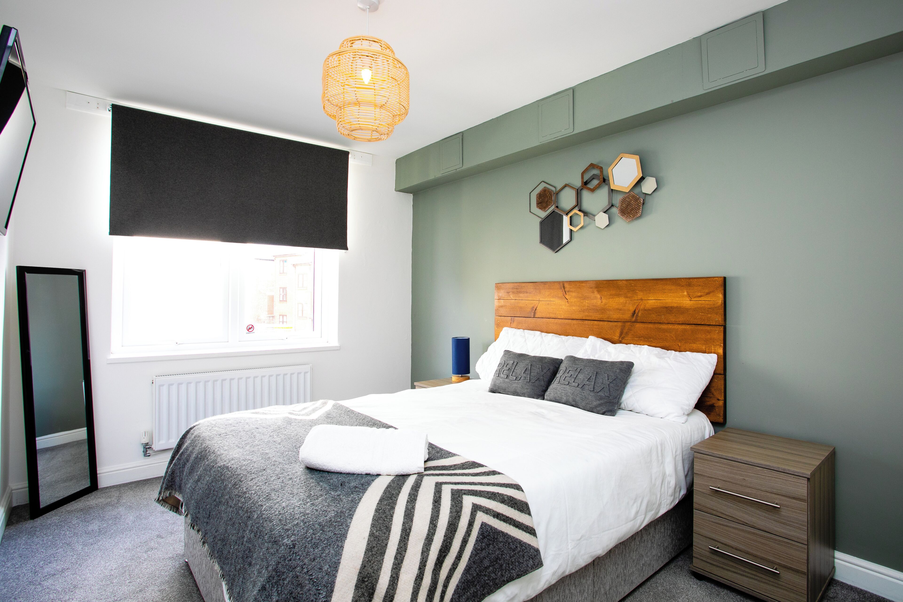 A bedroom with a bed, bedside table, and a wall-mounted light fixture.