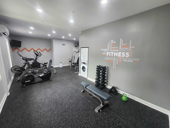 A gym with cardio equipment, dumbbells, and a wall with fitness-related words. - Dans Florida Condos Ocean Oasis at Runaway Bay (Bradenton Beach)