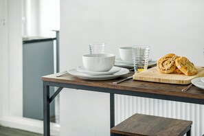 Une table à manger avec des assiettes, des bols, des verres et une planche à découper sur laquelle sont disposées des pâtisseries.