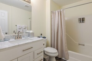 Un bagno con un lavandino bianco, un water e una tenda da doccia.