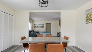 Un comedor con una mesa y sillas, un sofá al fondo y una puerta que conduce a otra habitación.