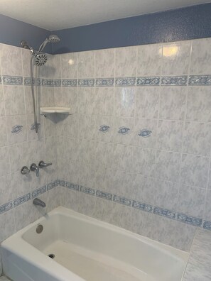 Ein Badezimmer mit Badewanne, Dusche und einem dekorativen Fliesenschmuck.