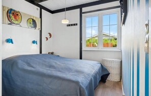 Ein Schlafzimmer mit einem großen Bett, einem Fenster mit Blick auf Grünflächen und Wandbildern.