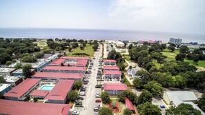 An aerial view of a residential area with multiple buildings, a swimming pool, and a view of the sea. - Cozy studio condo in Biloxi. Walk to the beach! (Biloxi)