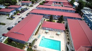 A multi-story hotel with red roofs, a swimming pool, and a parking lot. - Cozy studio condo in Biloxi. Walk to the beach! (Biloxi)
