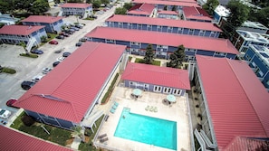 A multi-story hotel with red roofs, a swimming pool, and a parking lot. - Cozy studio condo in Biloxi. Walk to the beach! (Biloxi)
