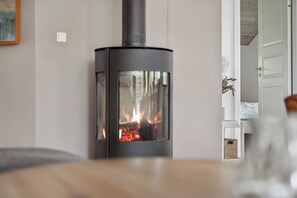 A room with a wood-burning stove, a bed, and a door leading to another room. - Lovely summer house near Rødby with spa sauna (Rødby)