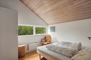 A bedroom with a sloped ceiling, a bed, a chair, a window, and a radiator. - Lovely summer house near Rødby with spa sauna (Rødby)