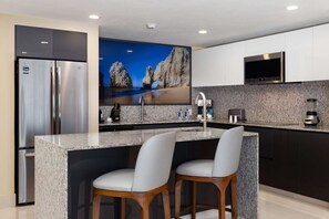 Una cocina moderna con encimeras de granito, electrodomésticos de acero inoxidable y una isla grande con taburetes de bar.