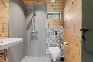 A compact bathroom with a shower, toilet, sink, and a window. - Charming tiny house in forest near sea peace now (Hasle)