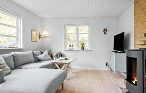 Ein modernes Wohnzimmer mit Sofa, Esstisch, Kamin und Fernseher.