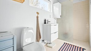 Et moderne badeværelse med toilet, vask og brusebad.