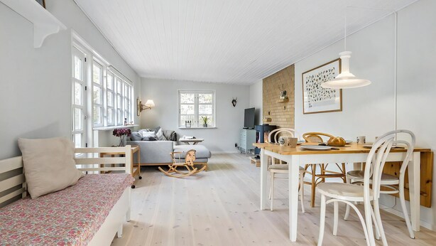 En hyggelig stue med sofa, spisebord med stole, fjernsyn og pejs.