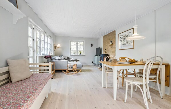 Ein gemütliches Wohnzimmer mit einer Couch, einem Esstisch mit Stühlen, einem Fernseher und einem Kamin.