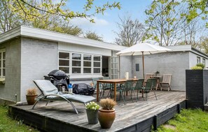 Eine moderne Terrassenanlage im Freien mit Esstisch, Stühlen und Grill.