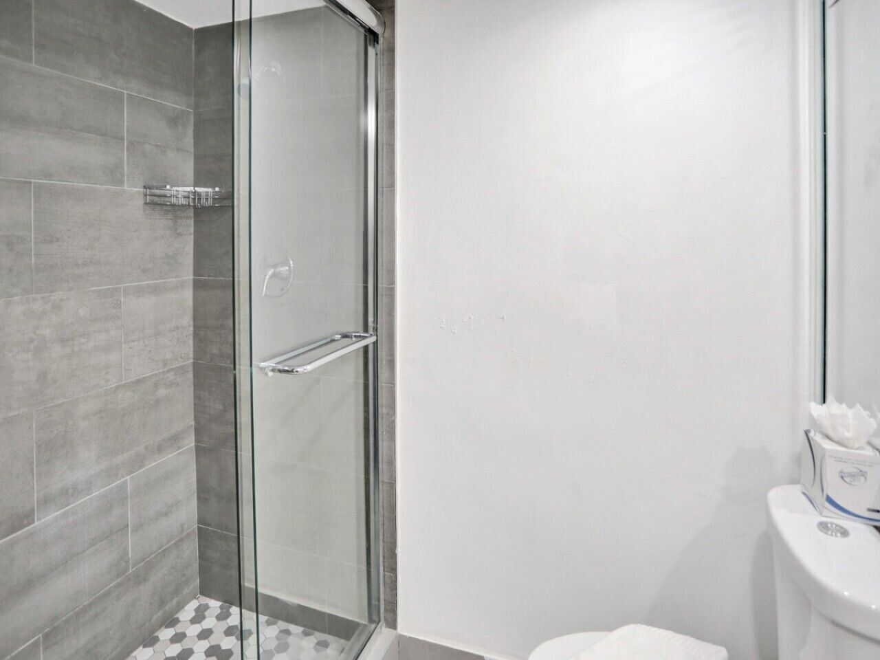A modern bathroom with a glass shower enclosure, a toilet, and a white sink.